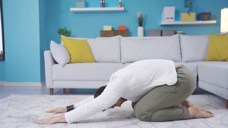 Fitness-instructor-showing-how-to-do-balasana-at-home-looking-at-camera.